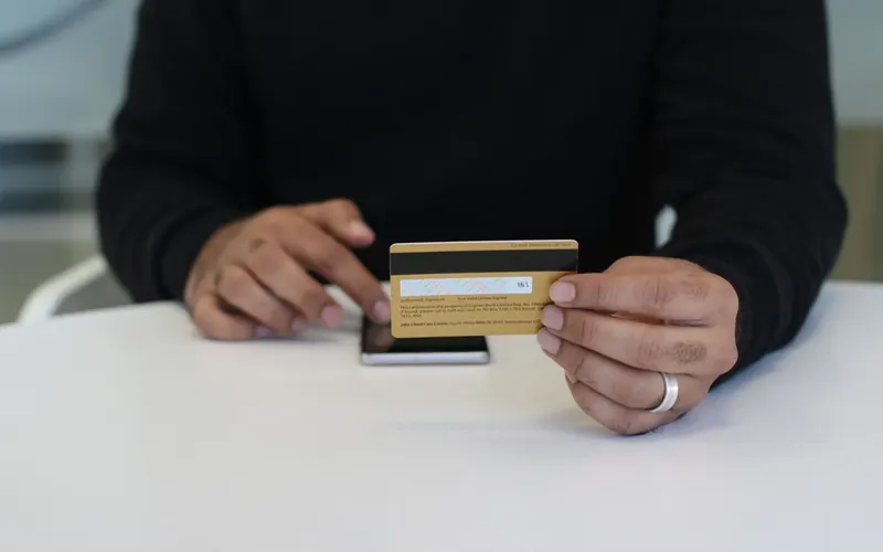 Manos con una tarjeta bancaria y un móvil