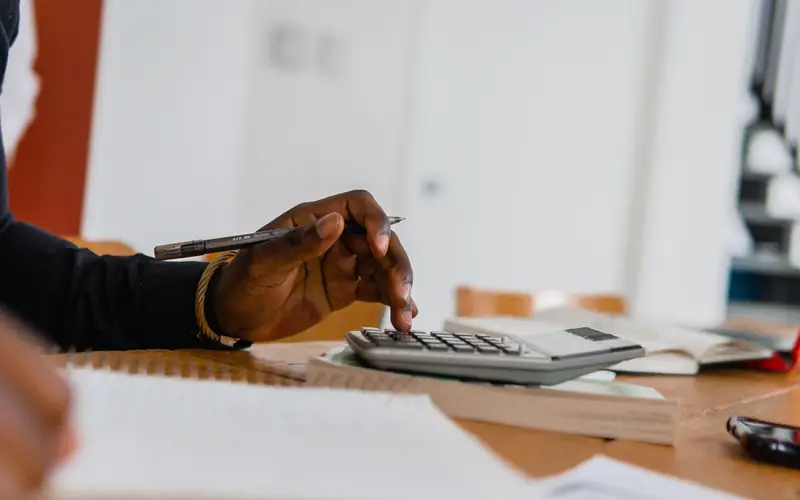 Persona haciendo cuentas con una calculadora y un bolígrafo
