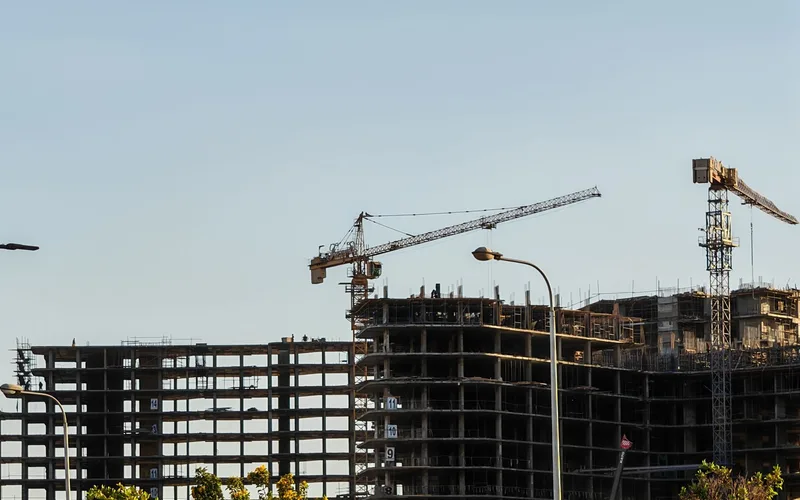 Edificios de viviendas en obra con dos grúas al atardecer