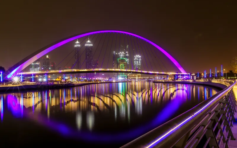 El Dubai Water Canal de noche, con el puente de la Tolerancia iluminado y torres de Business Bay al fondo